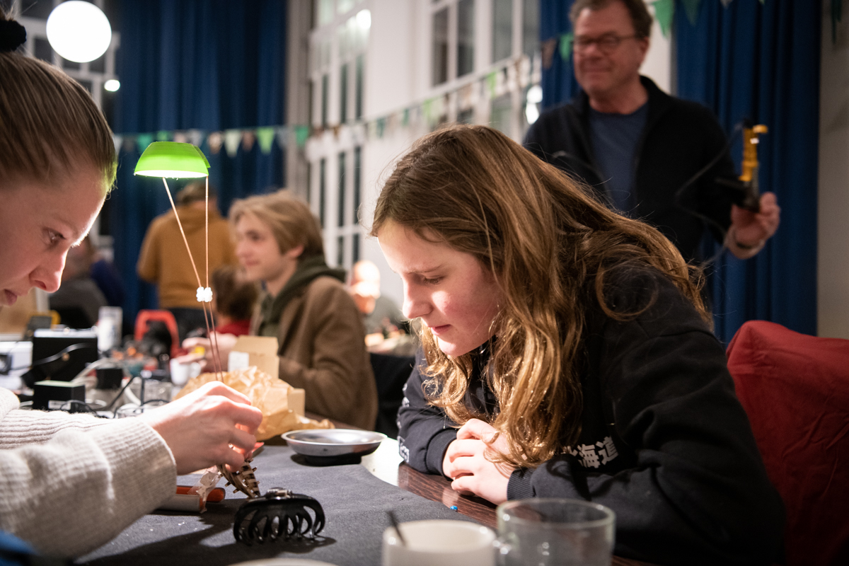 repaircafejeltje-foto-lucy-lambriex-ziebinnenzijde--2503 Twee jonge vrouwen werken aan een reparatie tijdens een avond van Repair Café Jeltje in Amsterdam West.